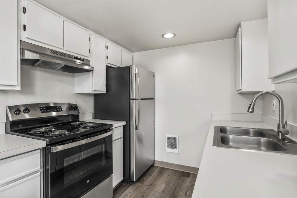 Modern kitchen with sleek white cabinets, stainless steel appliances, and a double sink at Cascade Ridge in Madras, Oregon