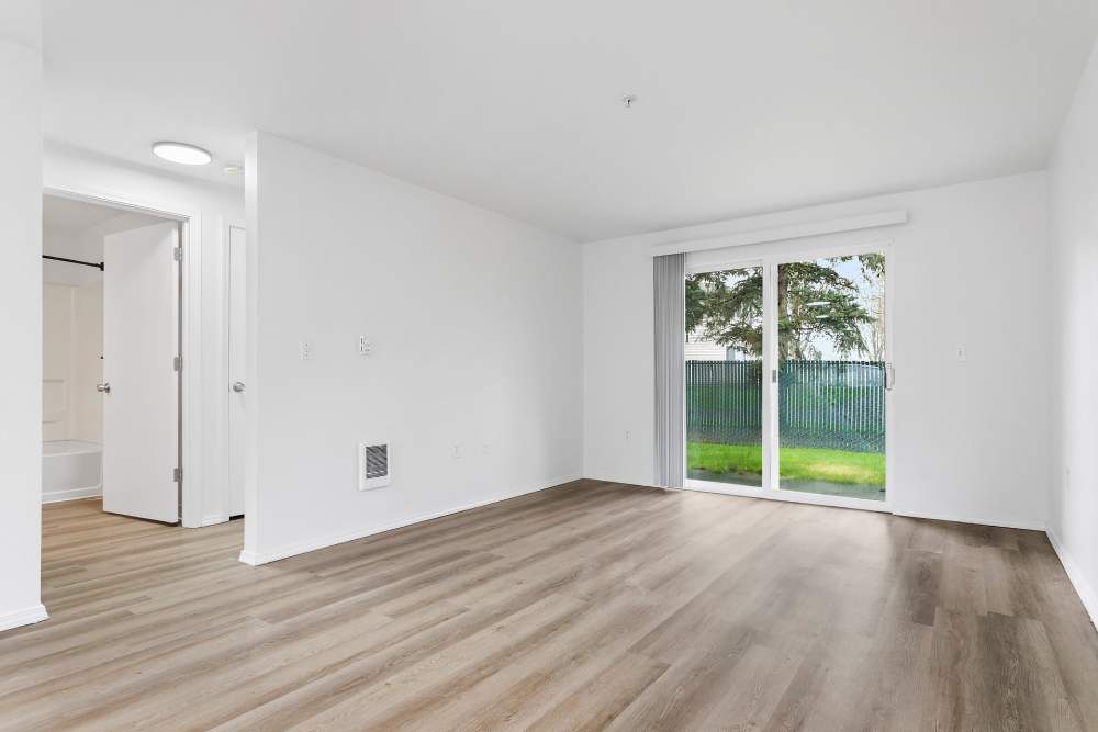 Living room with wood-style flooring and door to patio at Reedville Meadows in Beaverton, Oregon