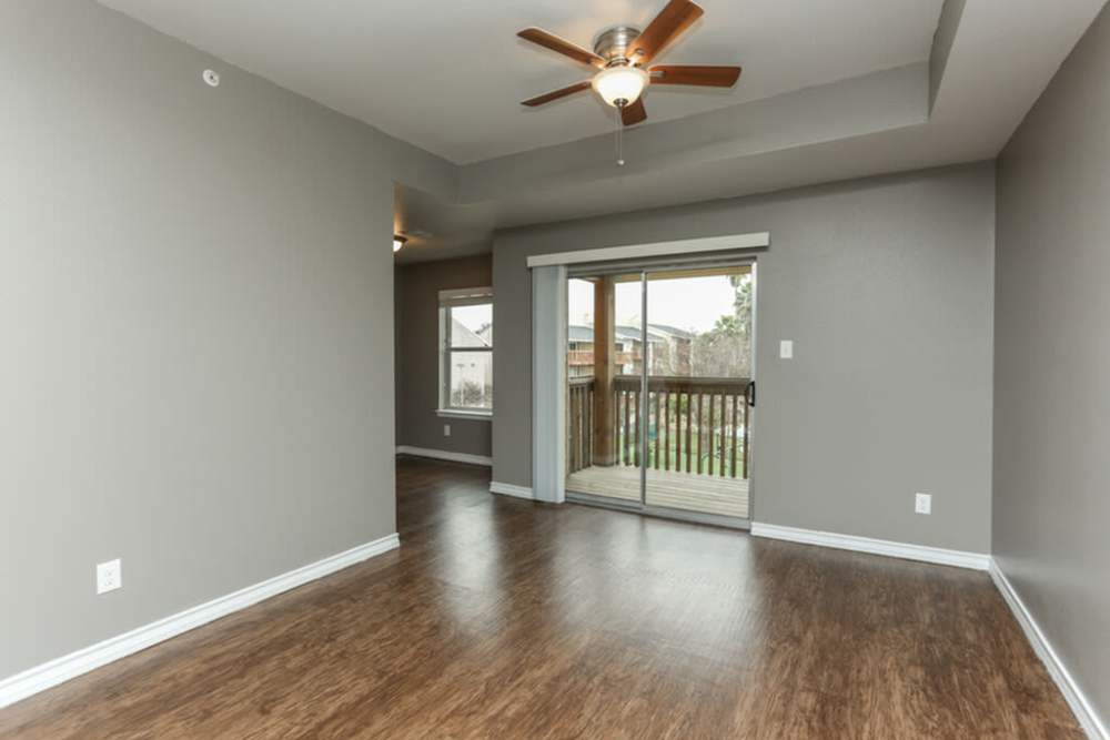 Living room with a ceiling fan and a sliding door leading to the private balcony at Palatia Apartment Homes in San Antonio, Texas