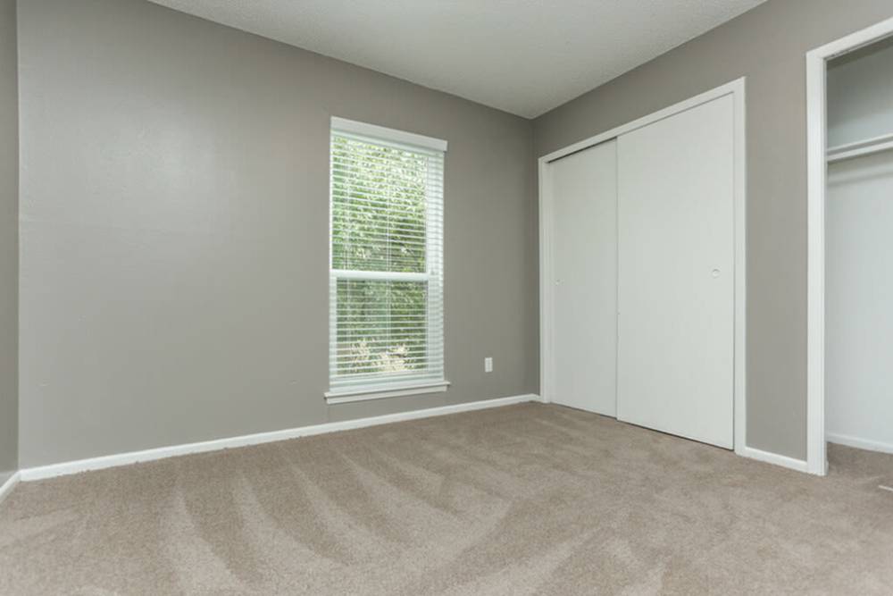 Bedroom with a large window and a walk-in closet at Palatia Apartment Homes in San Antonio, Texas