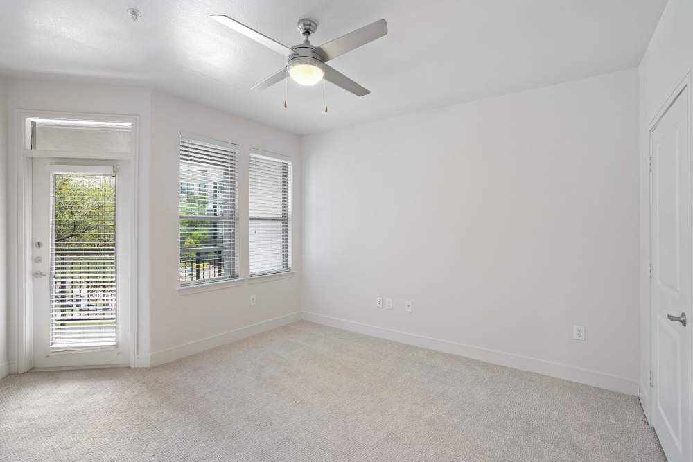 Bedroom with windows, ceiling fan and door leading to balcony at Trinity Bluff & Trinity District in Fort Worth, Texas