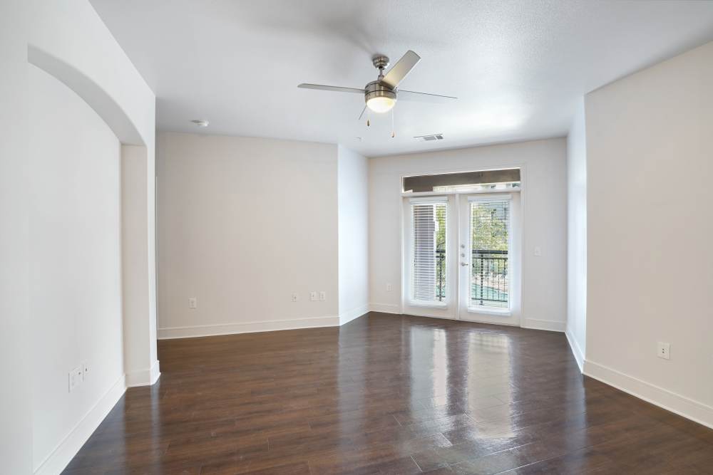 Living room with ceiling fan and door leading to balcony at Trinity Bluff & Trinity District in Fort Worth, Texas