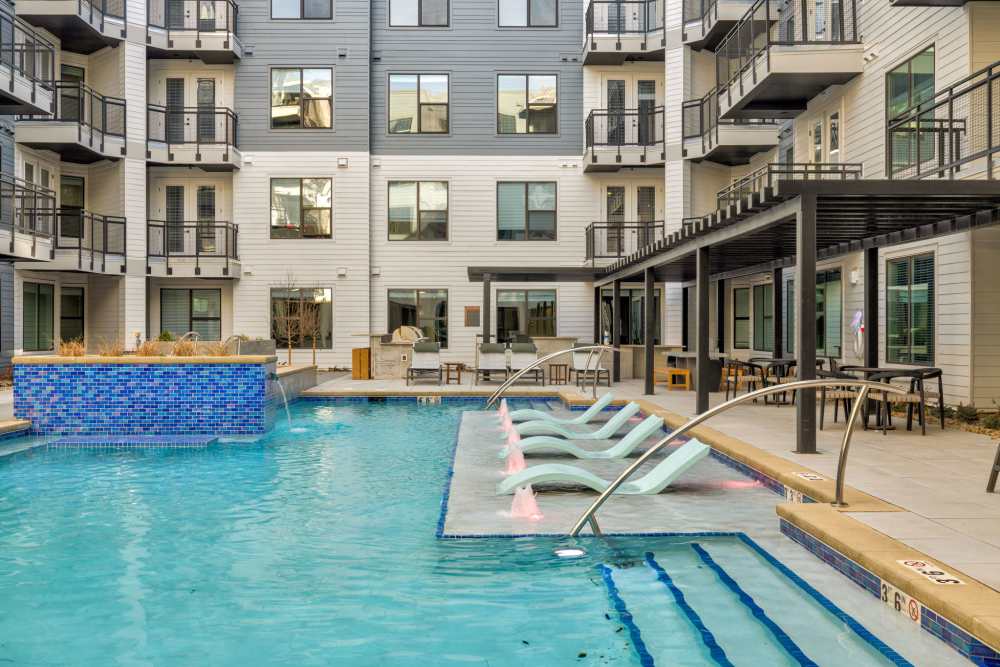 A clear blue swimming pool surrounded by lounge chairs at The Lock at Flatirons in Broomfield, Colorado