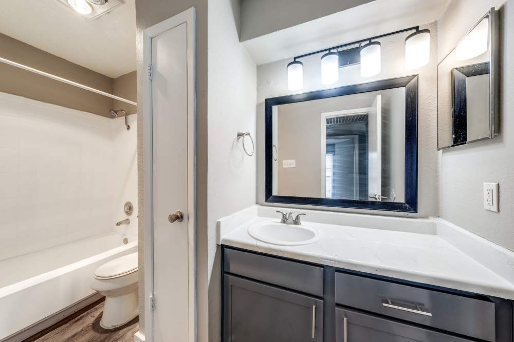 Apartment bathroom with a vanity unit and bath tub at Icon Apartments in San Antonio, Texas