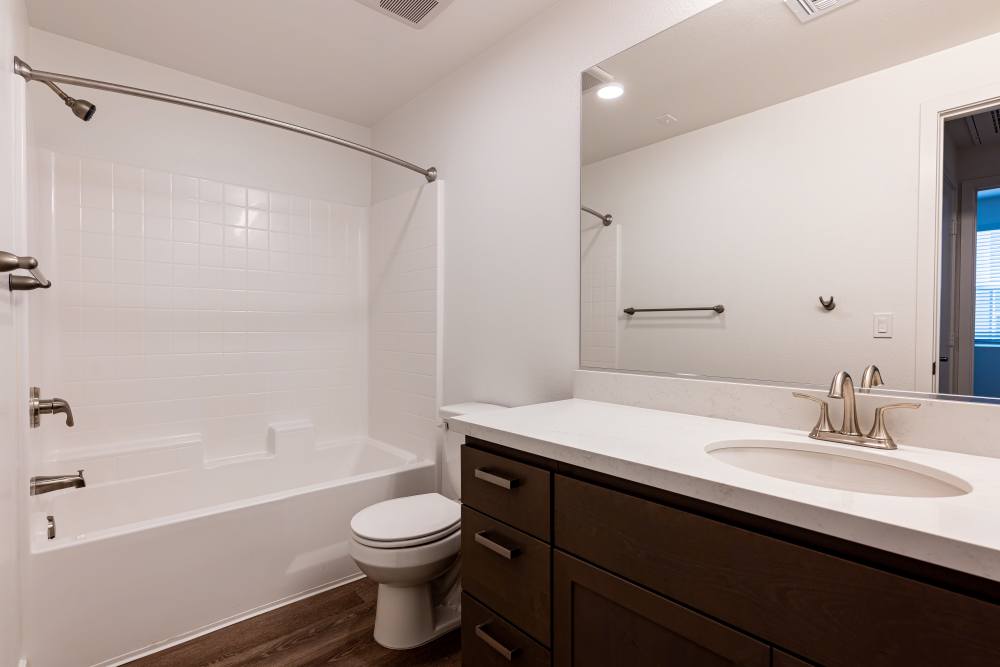 A spacious bathroom containing a toilet, sink, and shower at Monamos Terrace Apartments in Murrieta, California