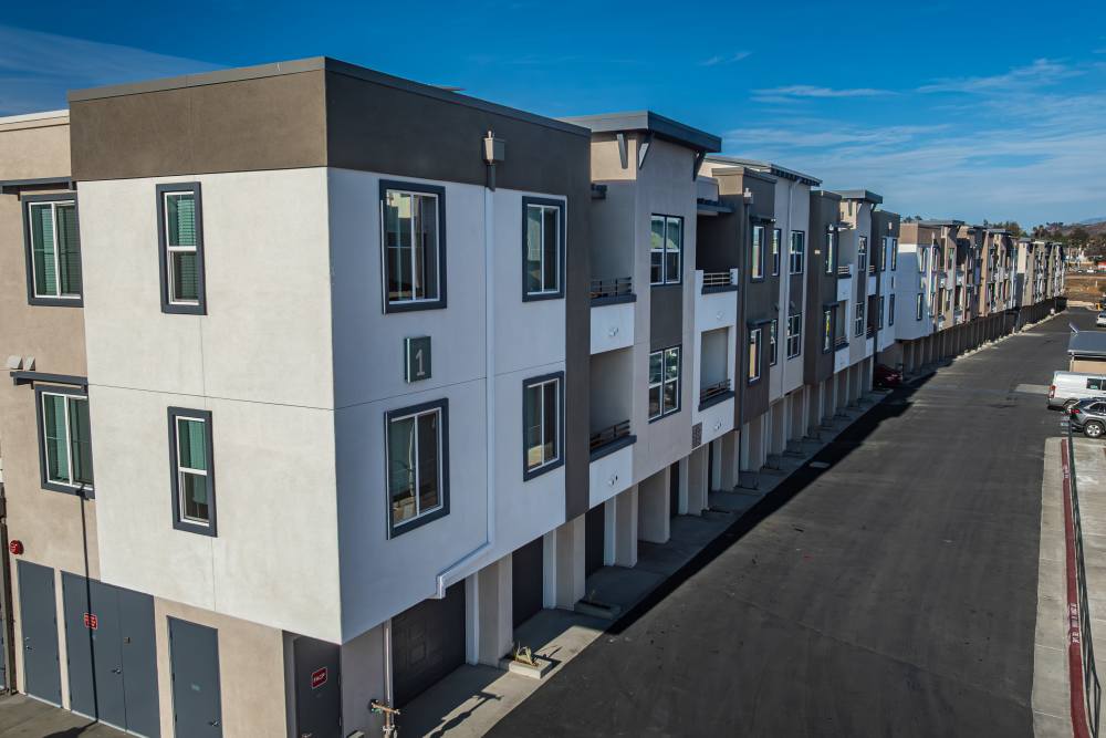 A street with several apartment buildings visible in the background, depicting a typical urban neighborhood setting at Monamos Terrace Apartments in Murrieta, California