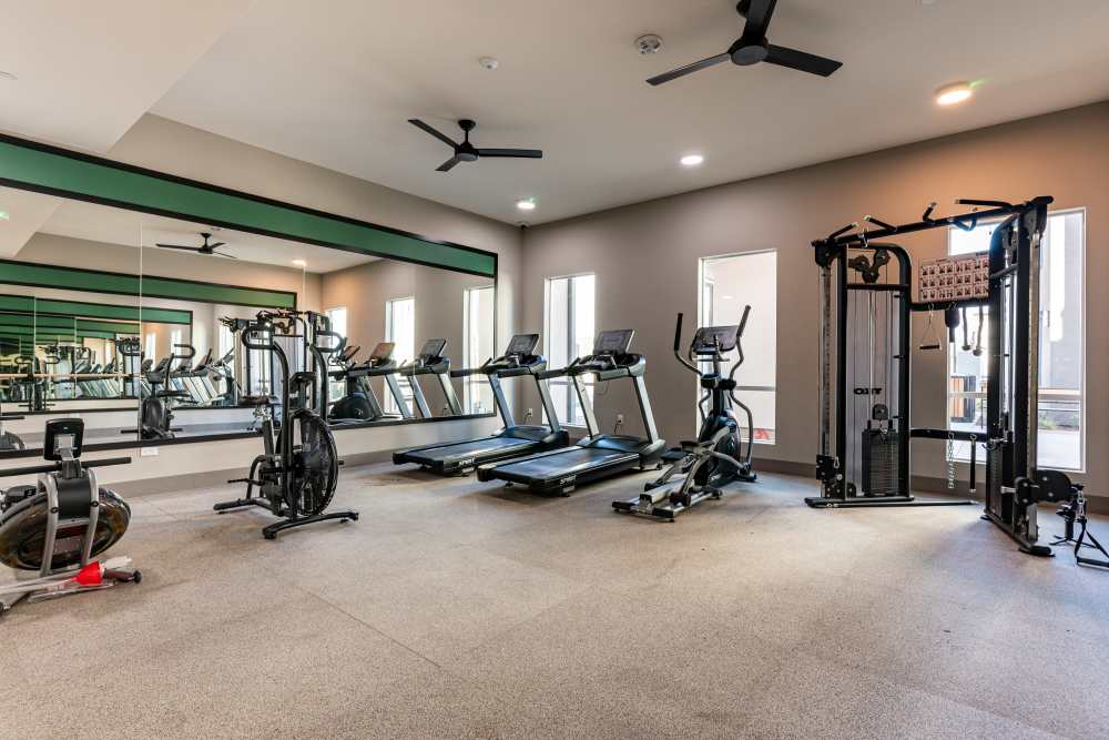 A gym room featuring several treadmills and large mirrors along the walls, creating a spacious workout environment at Monamos Terrace Apartments in Murrieta, California