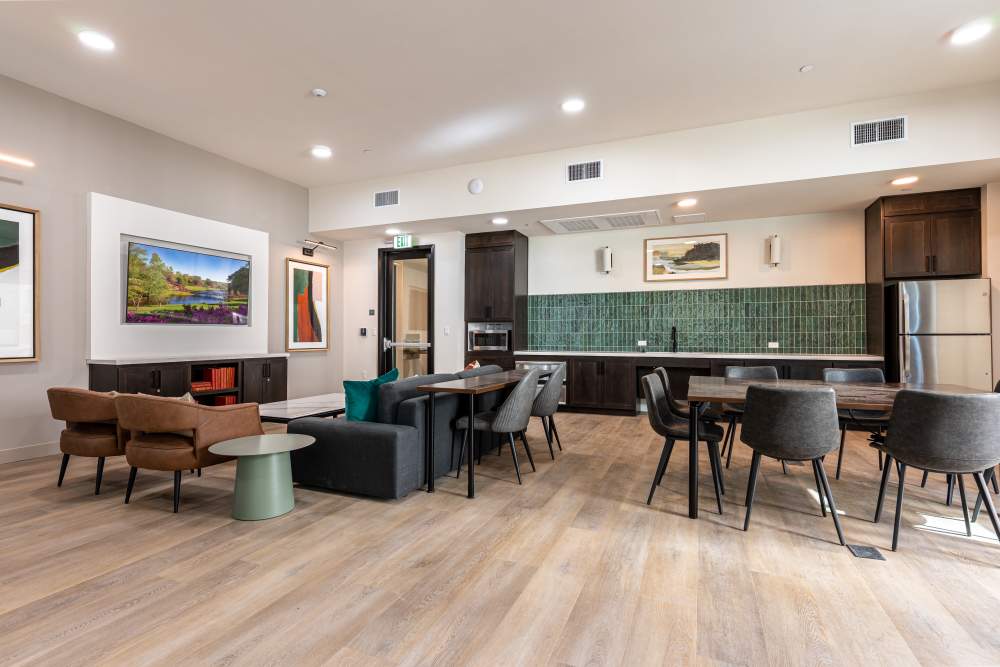 A modern kitchen and dining area featuring sleek appliances and a stylish table set for meals at Monamos Terrace Apartments in Murrieta, California