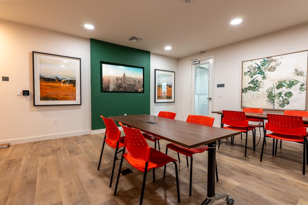 A spacious conference room equipped with red chairs and a rectangular table at Monamos Terrace Apartments in Murrieta, California
