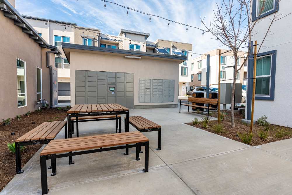 Outdoor patio featuring wooden benches and a grill at Monamos Terrace Apartments in Murrieta, California