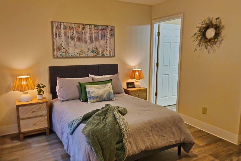 A cozy bedroom featuring a bed, two nightstands, and a decorative painting on the wall at Neawanna By The Sea in Seaside, Oregon