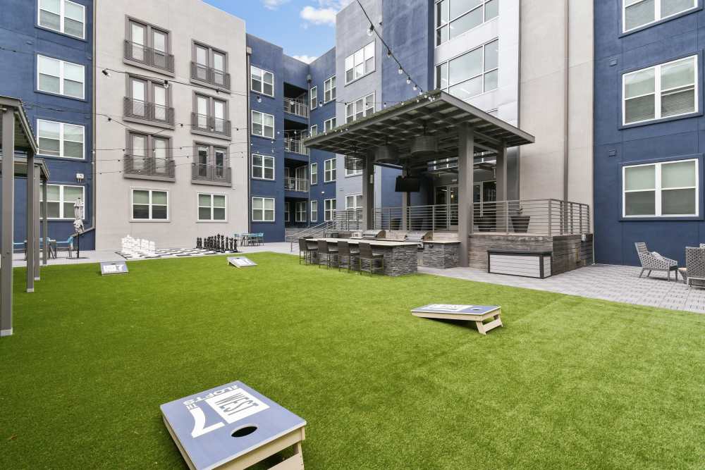 Apartment complex courtyard with a cornhole game and patio at The Lofts At West 7th in Fort Worth, Texas