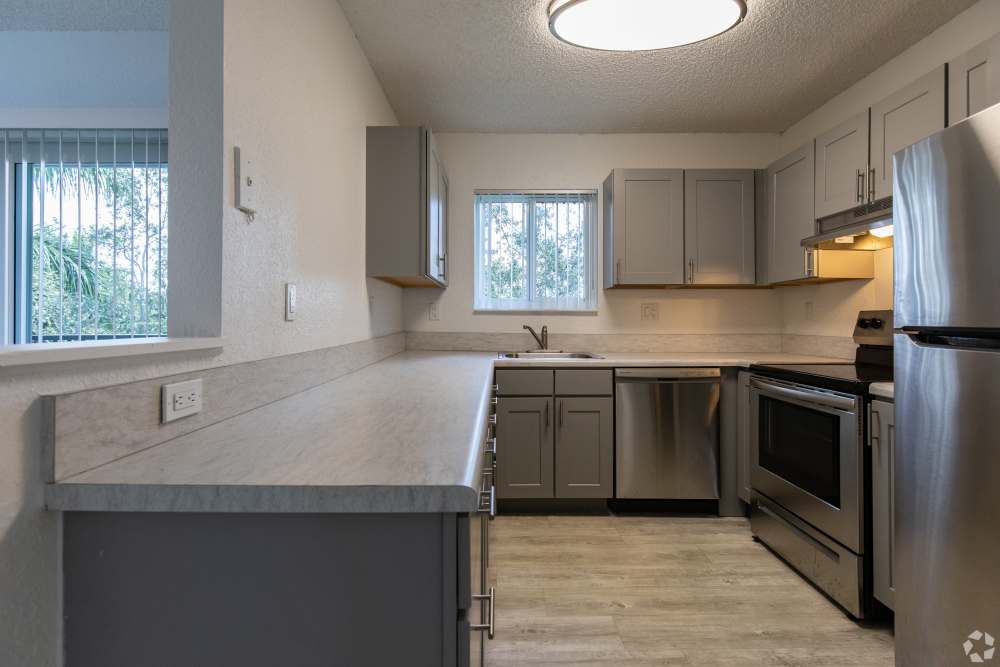 Modern kitchen with wooden cabinets and a refrigerator at Sunset Bay Apartments in Cutler Bay, Florida