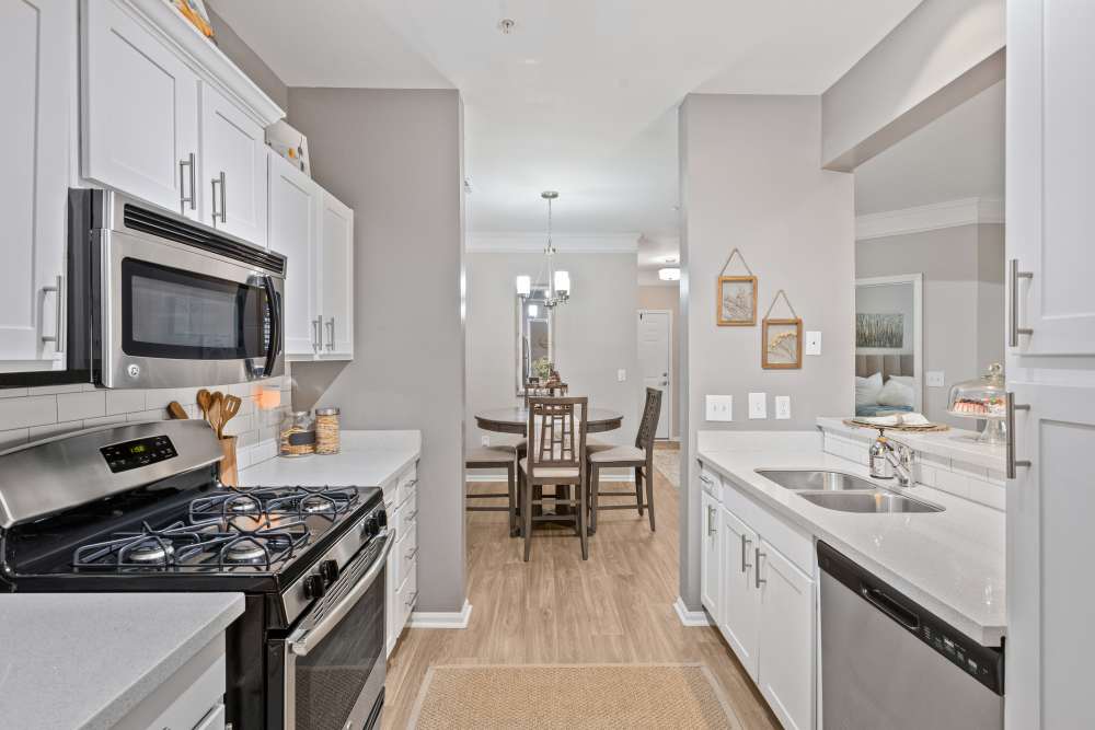 Modern kitchen with white cabinets, stainless steel appliances, and a gas stove at Retreat at Johns Creek in Duluth, Georgia