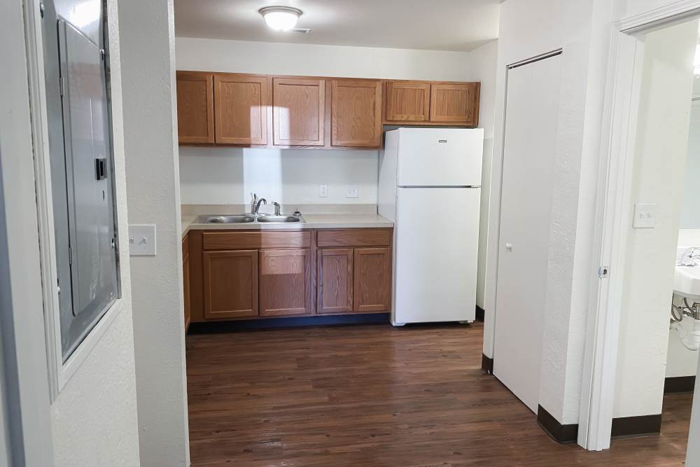 View of modern kitchen with wood-style flooring at Perry Acres Apartments in New Haven, Michigan