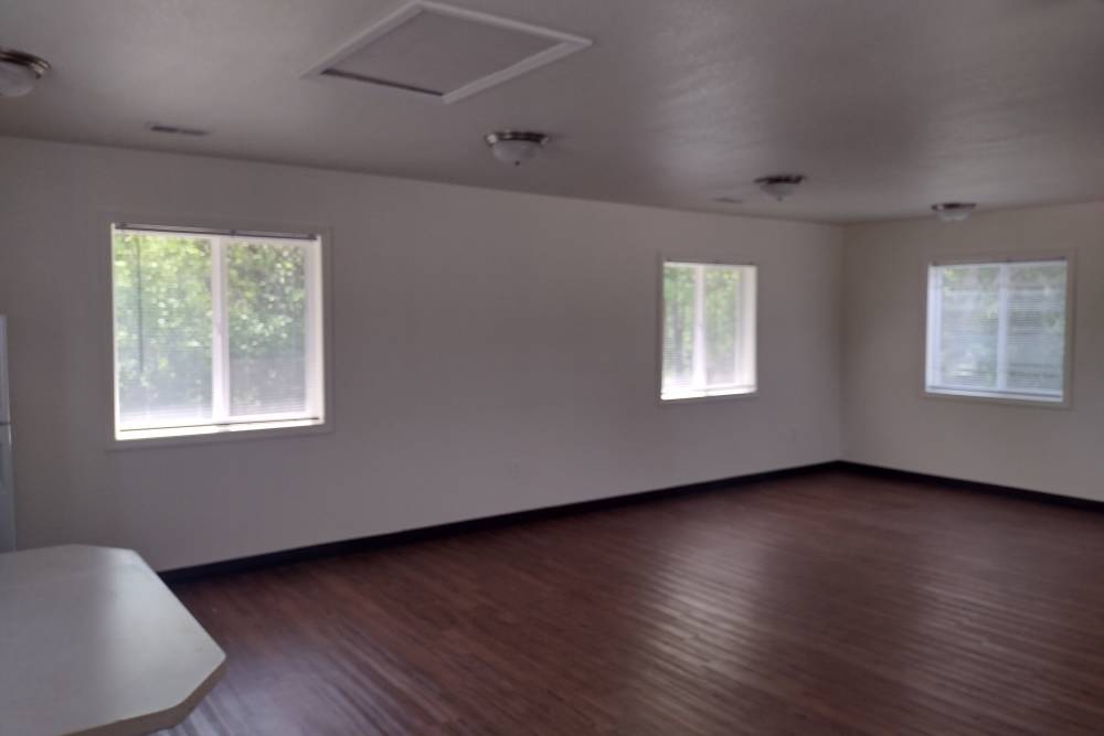 Community room with wood-style flooring at Perry Acres Apartments in New Haven, Michigan