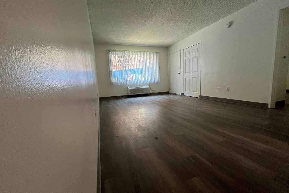 Spacious living room with big window and wood-style flooring at Valley Pride Village in Sylmar, California