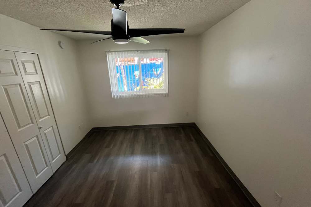 Bedroom with ceiling fan, big window and wood-style flooring at Valley Pride Village in Sylmar, California