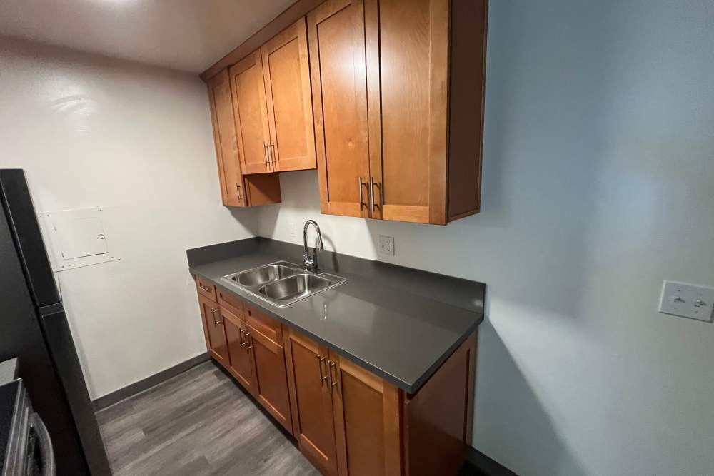 Kitchen with sink and wood-style cabinet at Valley Pride Village in Sylmar, California