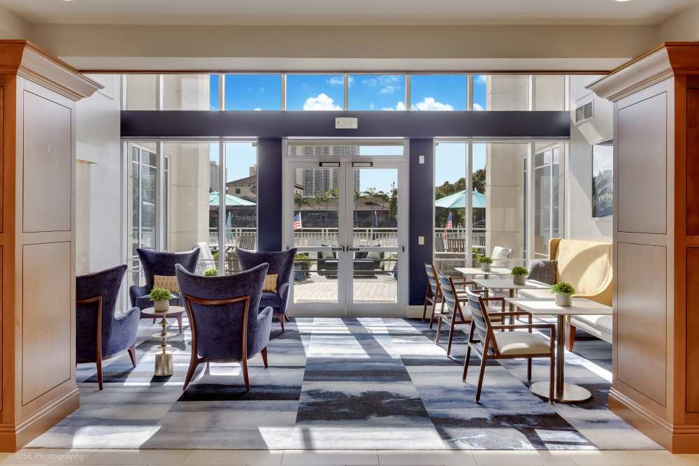 Bright clubhouse with floor-to-ceiling windows and modern furnishings at The Meridian at Waterways in Fort Lauderdale, FL