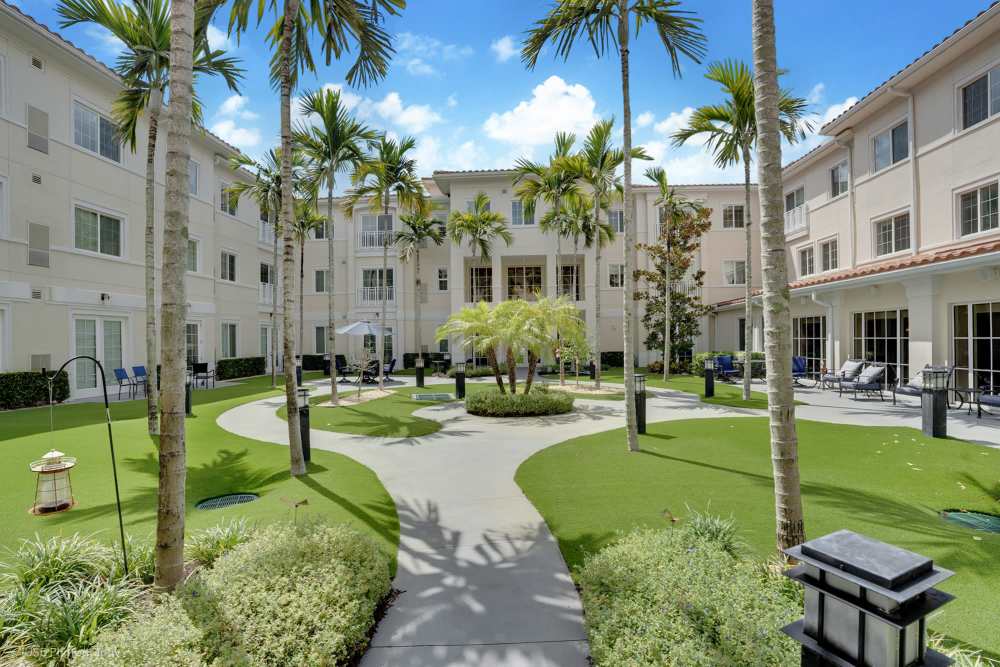 The courtyard at the senior living community in The Meridian at Boca Raton, featuring lush greenery and seating areas for residents at Boca Raton, Florida.