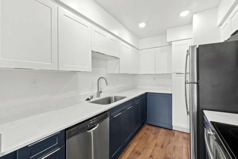 Kitchen with dark colored cabinets and white countertop at 1900 Ocean Apartment Homes in Long Beach, California