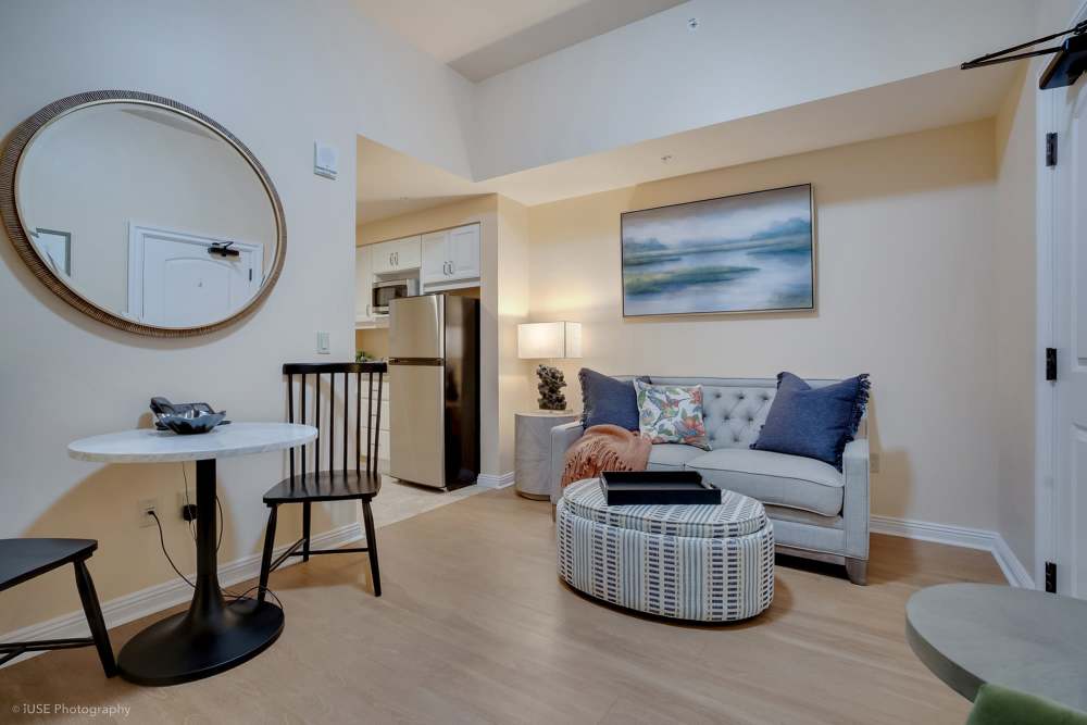 A cozy living room featuring a couch, chair, and mirror at The Meridian at Boca Raton in Boca Raton, Florida.