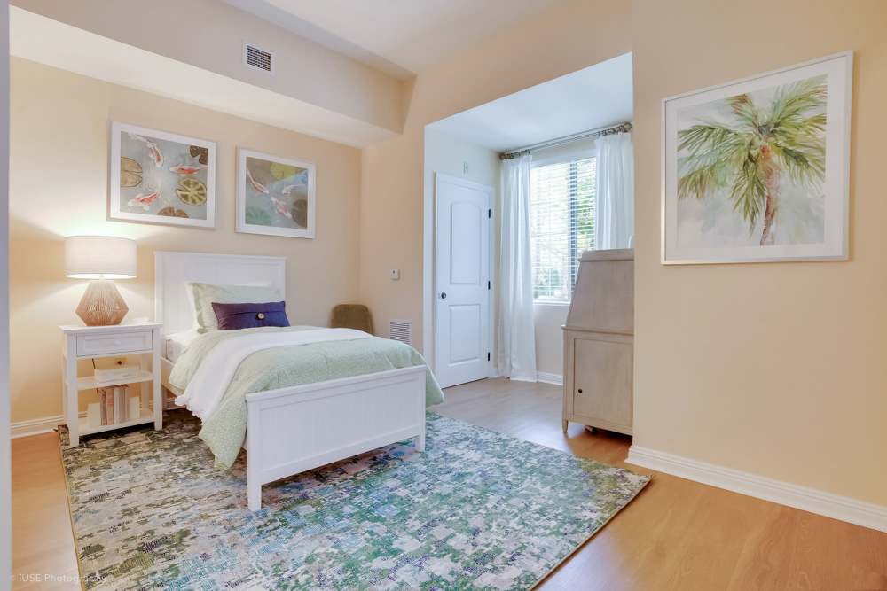 A cozy bedroom featuring a bed, dresser, and a painting at The Meridian at Boca Raton in Boca Raton, Florida.