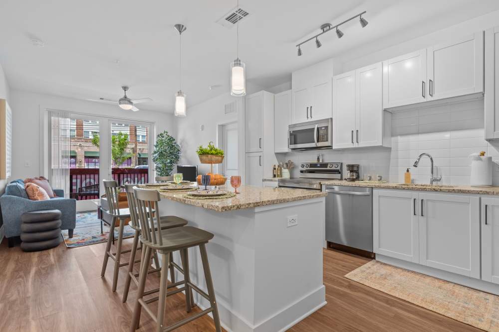 Modern kitchen with an island and dining area, leading to a balcony at Flats at College Park in College Park, Maryland
