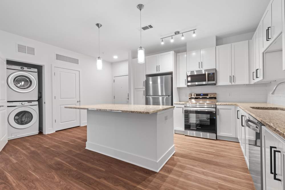 Modern kitchen with island and stainless appliances at Flats at College Park in College Park, Maryland.