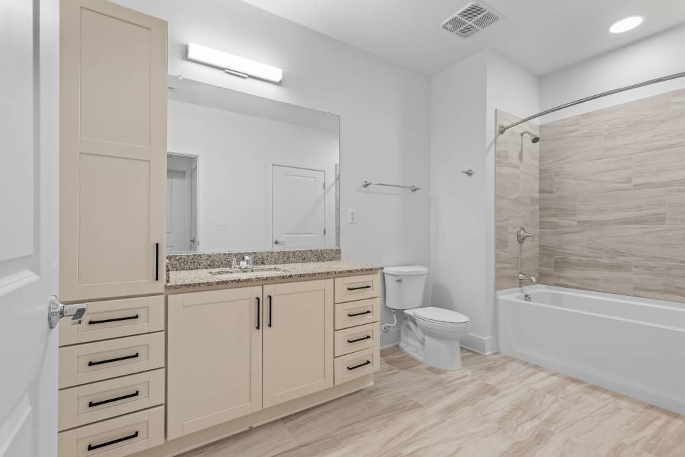 Elegant bathroom with beige cabinetry and a tub at Flats at College Park in College Park, Maryland.