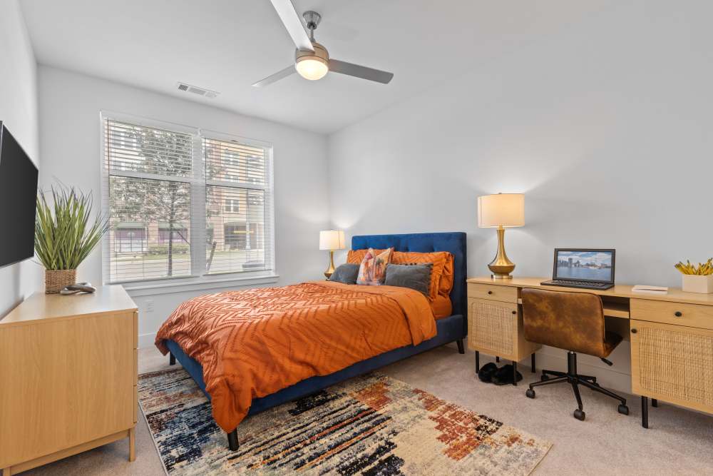 Stylish bedroom with orange accents and a workspace at Flats at College Park in College Park, Maryland.