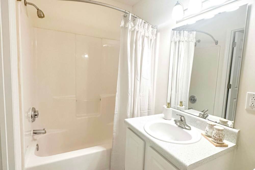 Bright bathroom with a bathtub and shower curtain at Orchard Trace Gastonia in Gastonia,North Carolina