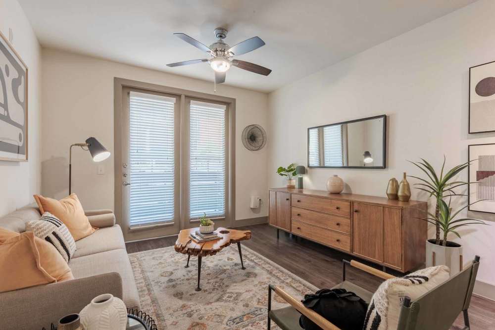 A cozy living room featuring a couch, chair, and television at Henley at The Rim in San Antonio, Texas.