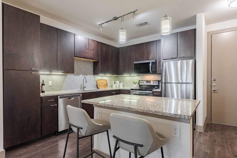 Stylish kitchen showcasing stainless steel appliances and wooden floors at Henley at The Rim, San Antonio, Texas.