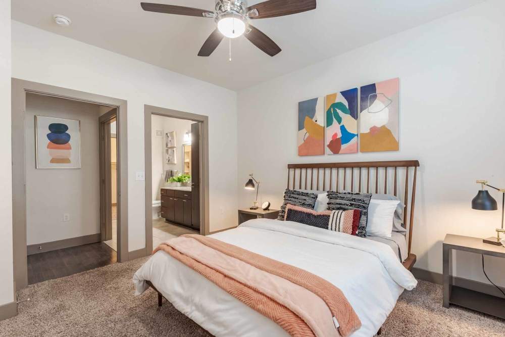 A cozy bedroom featuring a ceiling fan and a neatly made bed at Henley at The Rim in San Antonio, Texas.