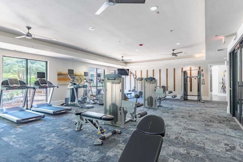 A gym room featuring exercise equipment and a ceiling fan at Henley at The Rim in San Antonio, Texas.
