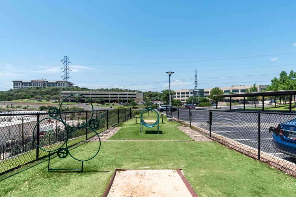 A green grassy area featuring a playground and a parked car at Henley at The Rim in San Antonio, Texas.
