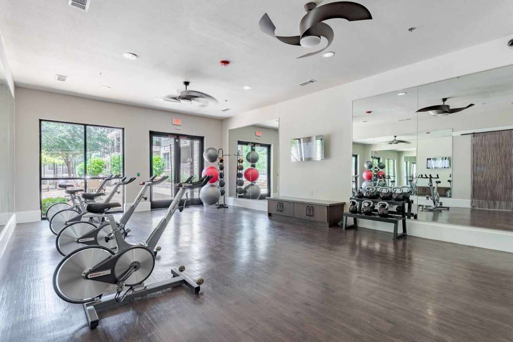 A gym room featuring exercise equipment and mirrors at Henley at The Rim in San Antonio, Texas.
