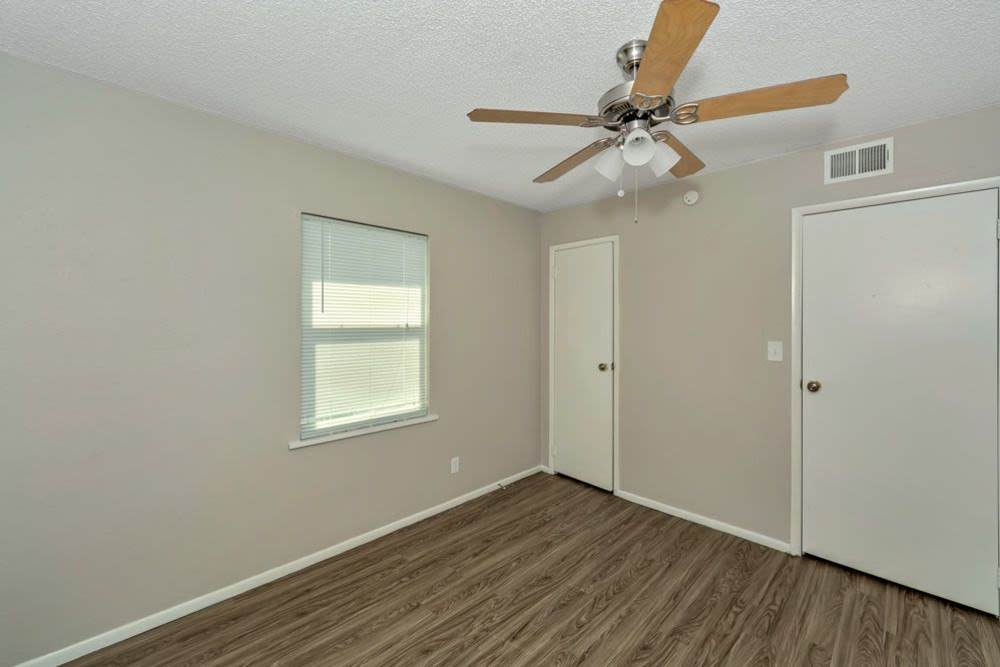 Spacious bedroom with wood-style flooring and ceiling fan at The Residence At Okemah in Okemah, Oklahoma, 