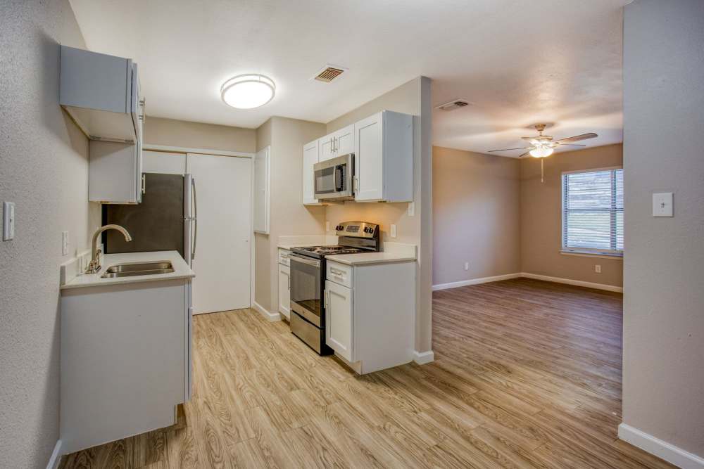 View of fully equipped kitchen and spacious living area with ceiling fan at The Summit Apartments in Athens, Texas