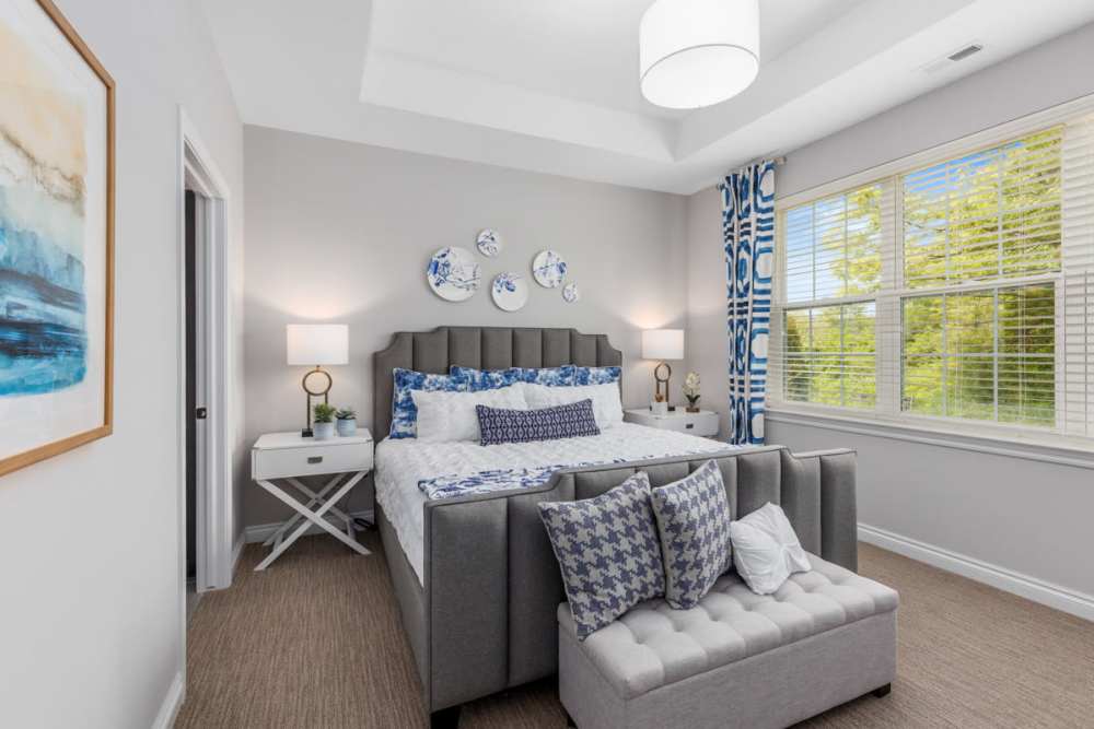 Spacious bedroom with king size bed, side table lamp and large window at Encore at West Valley in White Lake, Michigan