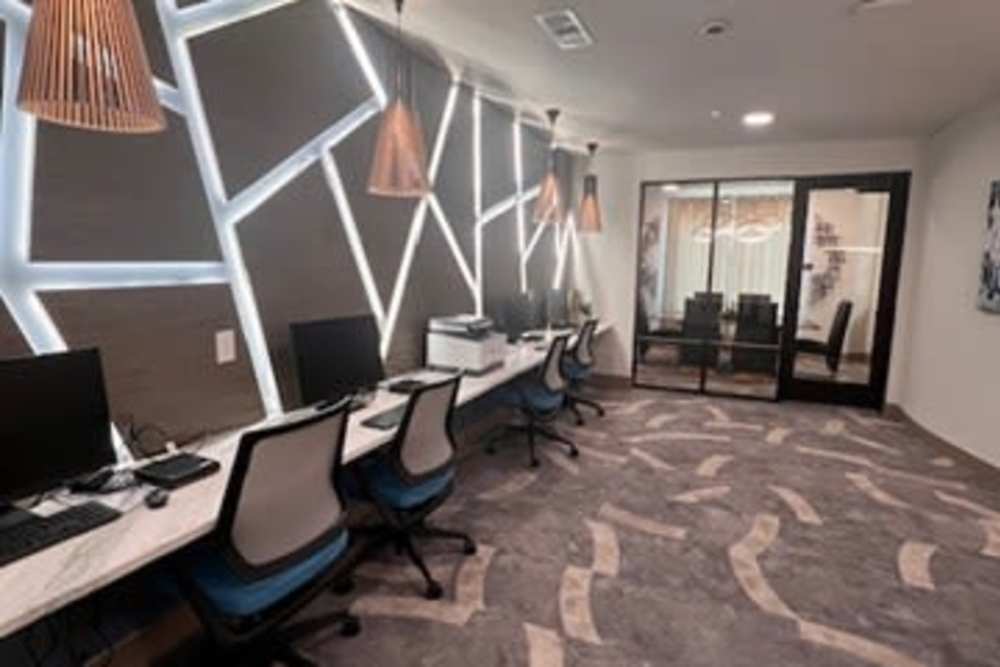 Office space featuring a large desk with multiple computer monitors at The Heyward Apartments, Corinth, Texas.