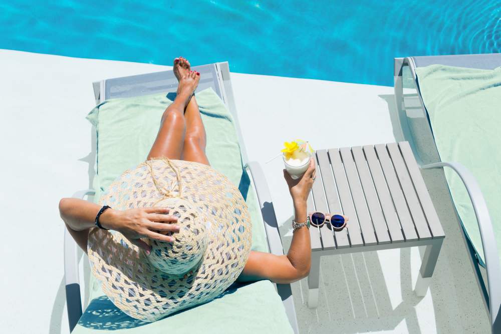 Woman in a hat sits comfortably on a lounge chair next to pool at Union at the Park in Denver, Colorado