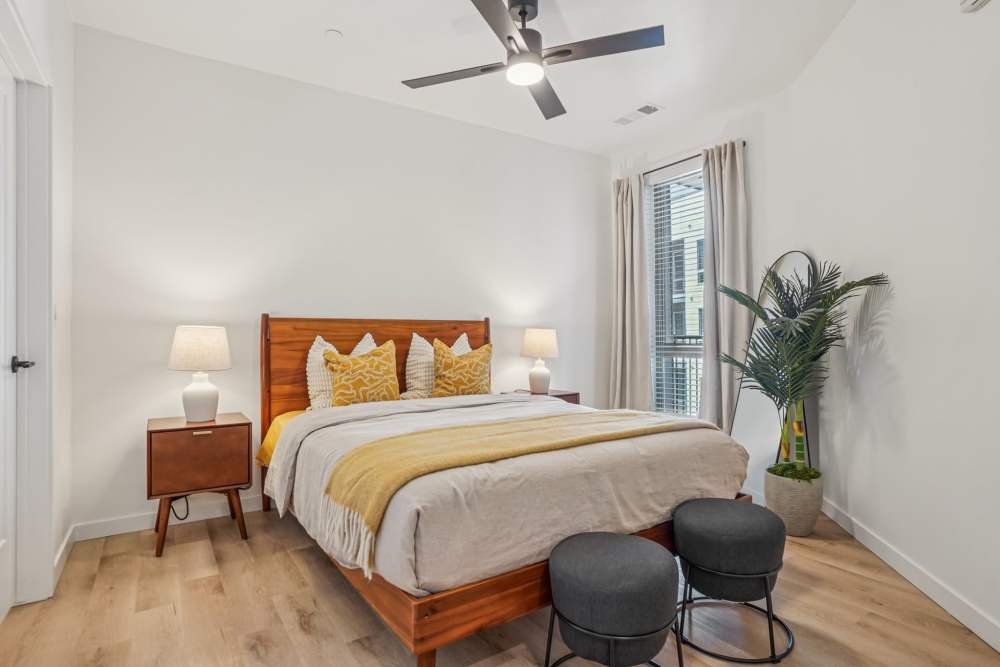 Cozy bedroom featuring a large bed with decorative pillows, bedside tables, and natural light from windows at Tempo at Nine Mile Station in Aurora, Colorado.