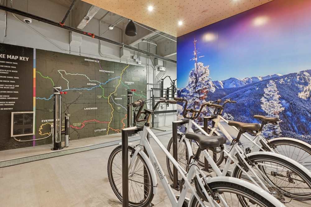 Indoor bike storage with white bikes, trail map, and mountain mural at Tempo at Nine Mile Station in Aurora, Colorado
