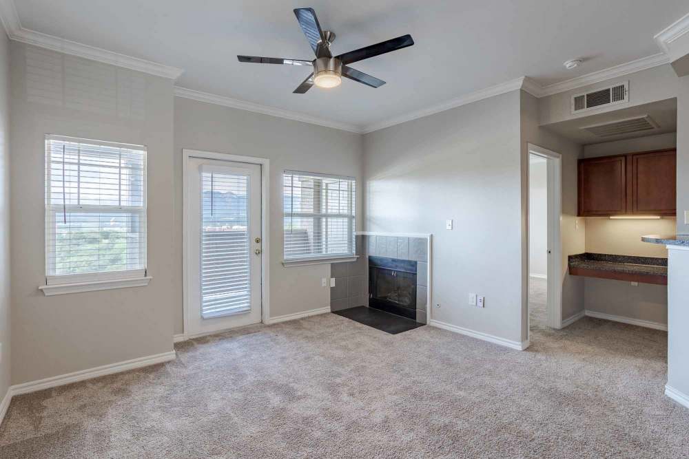 Cozy living space with soft carpeting, large windows for natural light, a ceiling fan, and a private balcony door, at Bella Springs Apartments in Colorado Springs, Colorado.