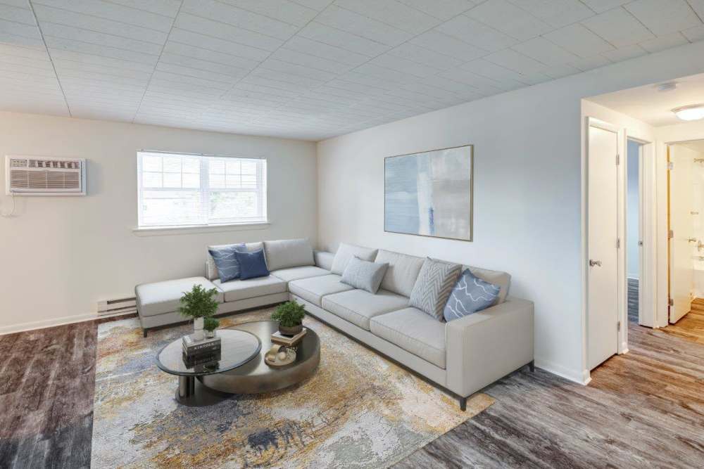 Spacious living room with couch, wood-style flooring and open layout connecting to kitchen at Quakertown West Apartment Homes in Quakertown, Pennsylvania