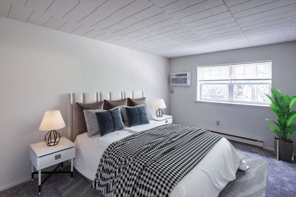 Spacious bedroom with large comfortable bed, wooden floor and large window at Quakertown West Apartment Homes in Quakertown, Pennsylvania
