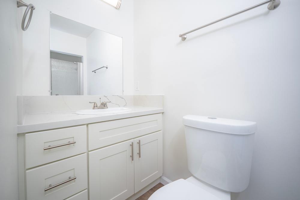 Contemporary bathroom with a white vanity, sink, and toilet, featuring a clean design and ample natural light, at Copa Cabanas in Santa Cruz, California.